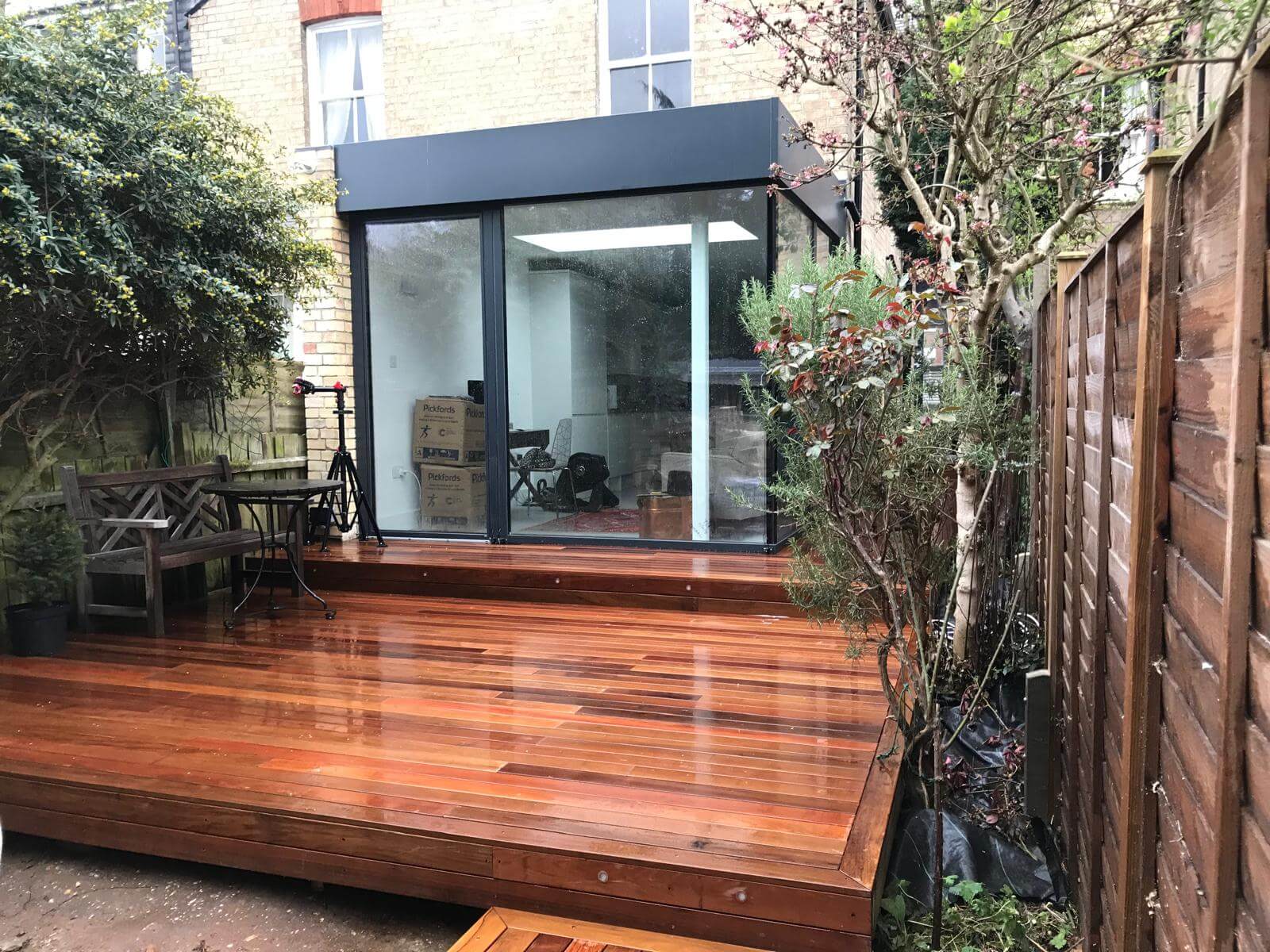 A wooden decking with a glass door, perfect for relaxing afternoons—consider expert Sash Window Repair South London to keep your windows in top condition and complement your outdoor space.